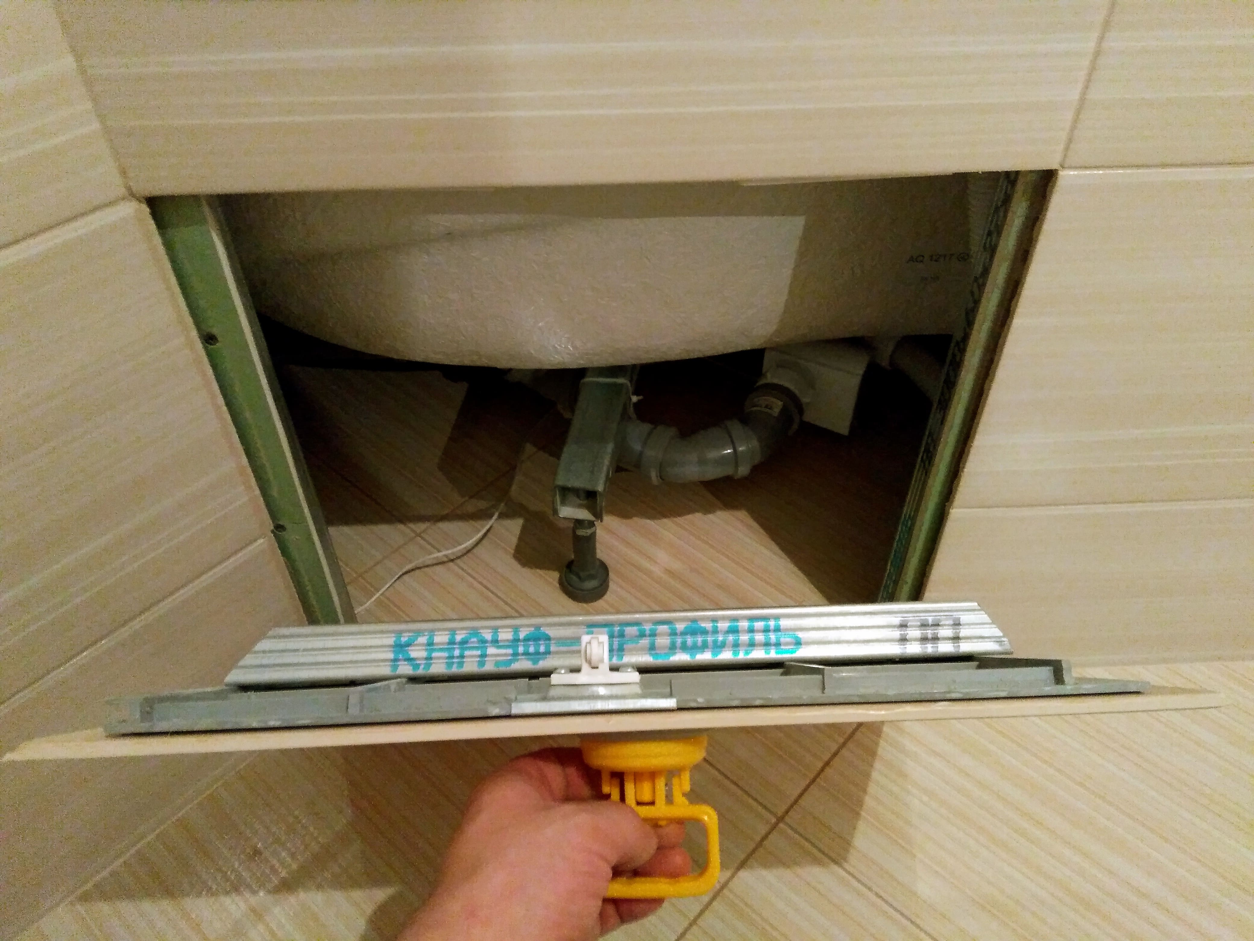 Открытый пластиковый люк под плитку в экране ванны.